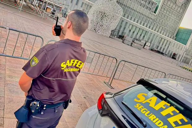 Vigilante de Saffer hablando por radio junto al coche de la empresa en una ronda